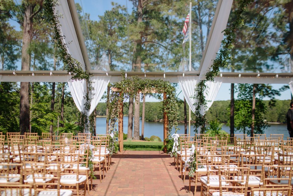 country club wedding under clear top tent with gold chiavari chairs and greenery