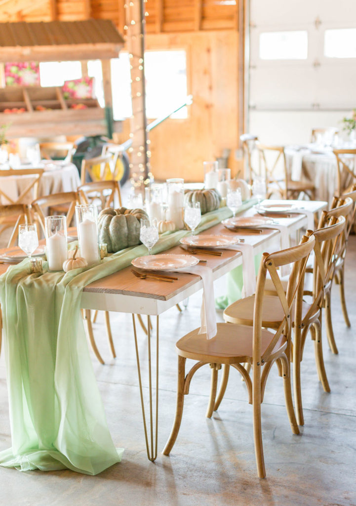 Farm Table with x back seating. White pumpkins & Candles. Sage runner. Barn wedding